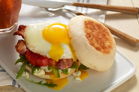 sunny side up egg on top of meat, veggies, and Bays English Muffins