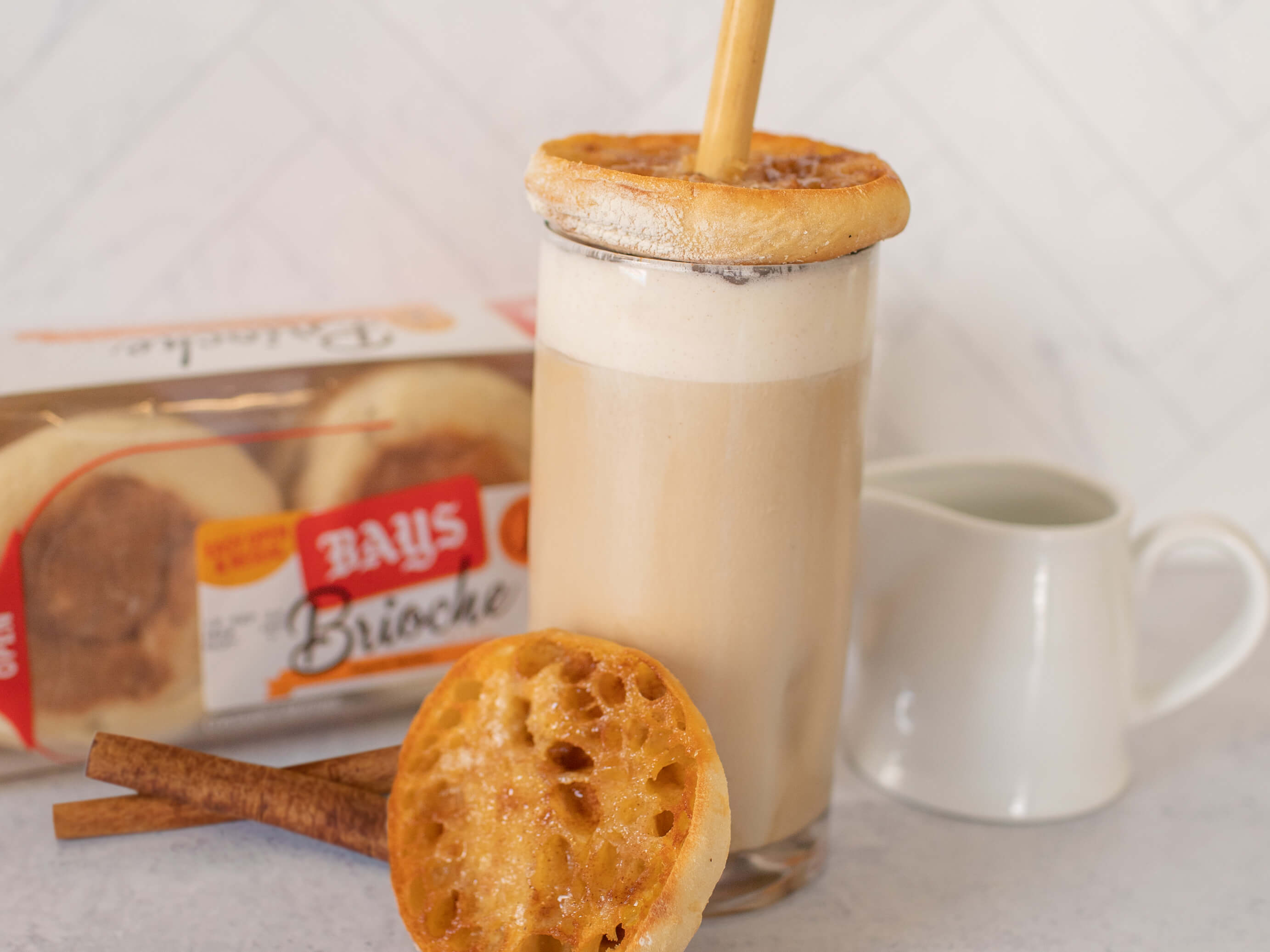 GLASS OF ICED COFFEE WITH A TOASTED BAYS AT THE TOP AND A STRAW POKING THROUGH