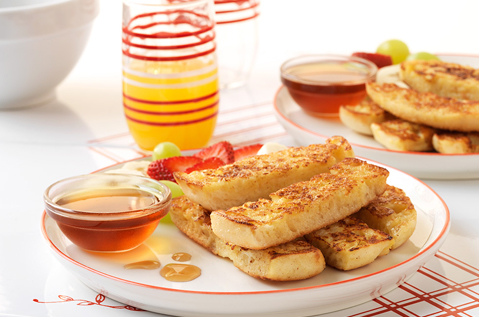 STRIPS OF BAYS STACKED ON A PLATE NEXT TO A DISH OF MAPLE SYRUP