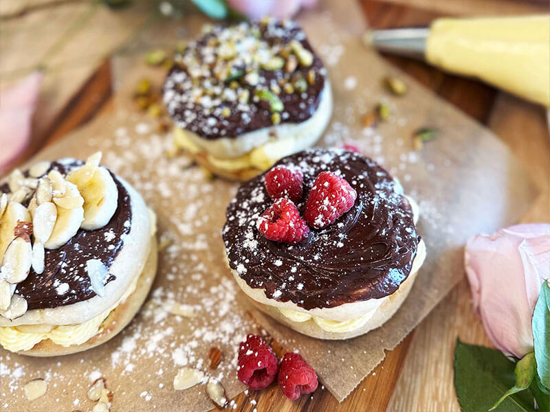 THREE BAYS FILLED WITH CREAM COVERED IN CHOCOLATE WITH FRUIT NUTS AND POWDERED SUGAR