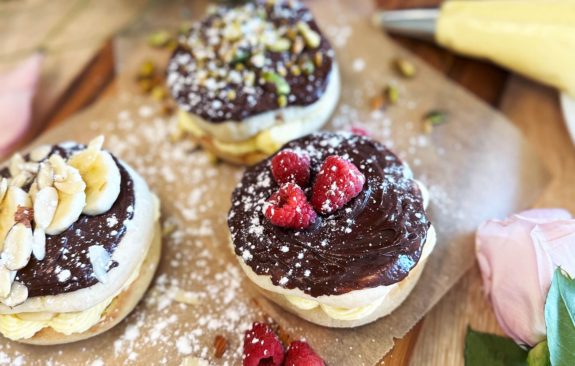 THREE BAYS FILLED WITH CREAM COVERED IN CHOCOLATE WITH FRUIT NUTS AND POWDERED SUGAR