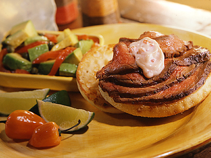 SLICES OF MEDIUM RARE BEEF ON BAYS NEXT TO LIMES AND PEPPERS