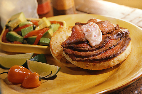 SLICES OF MEDIUM RARE BEEF ON BAYS NEXT TO LIMES AND PEPPERS