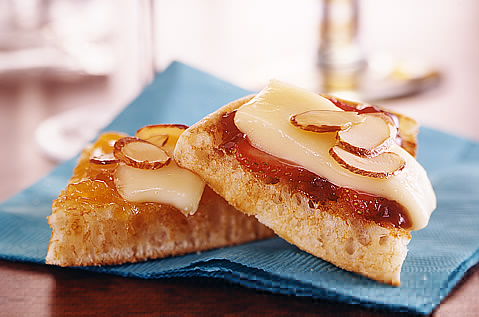 A wedge of a bays english muffin topped with cheese, fruit and almonds