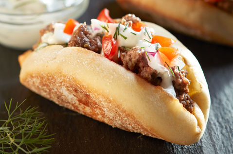 ENGLISH MUFFIN FOLDED IN HALF FILLED WITH MEAT AND TZATZIKI SAUCE