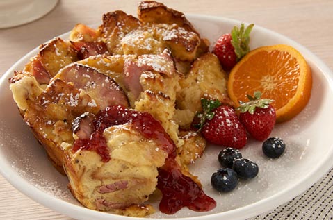 BAYS CASSEROLE WITH HAM AND EGGS ON A PLATE WITH FRUIT