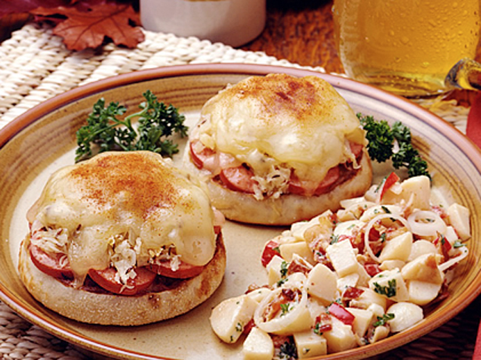 PLATE WITH TWO ENGLISH MUFFINS COVERED WITH MELTY CHEESE, MEAT MIX AND TOMATOES