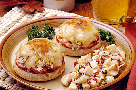 PLATE WITH TWO ENGLISH MUFFINS COVERED WITH MELTY CHEESE, MEAT MIX AND TOMATOES