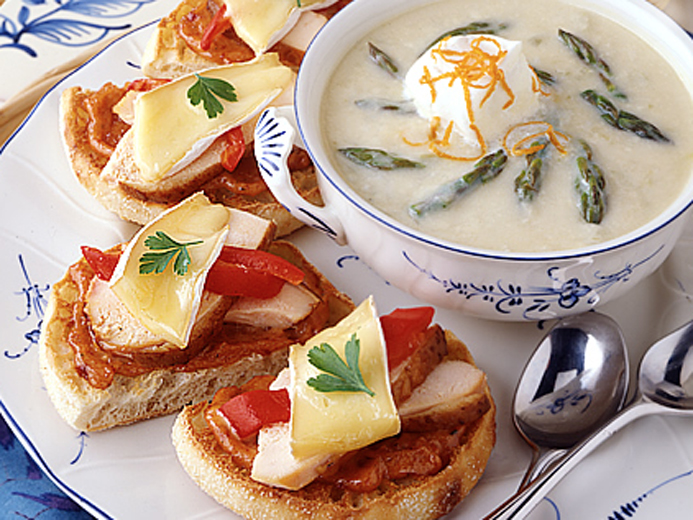 SLICED BAYS TOPPED WITH MEAT, TOMATO AND CHEESE NEXT TO A WHITE BISQUE