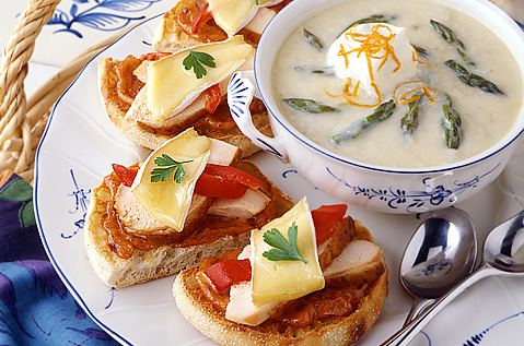 SLICED BAYS TOPPED WITH MEAT, TOMATO AND CHEESE NEXT TO A WHITE BISQUE