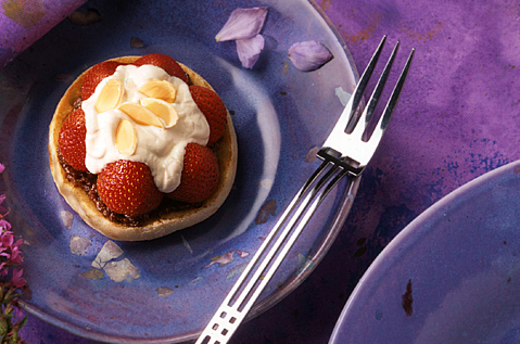 BAYS TOPPED WITH FRUIT AND CREAM ON A PURPLE PLATE