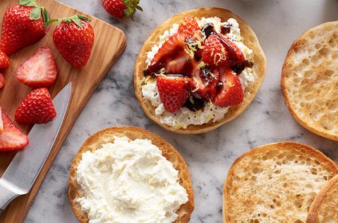 BAYS FACE UP ON A WHITE GRANITE COUNTERTOP COVERED IN WHITE CHEESE FRUIT AND A DRIZZLE