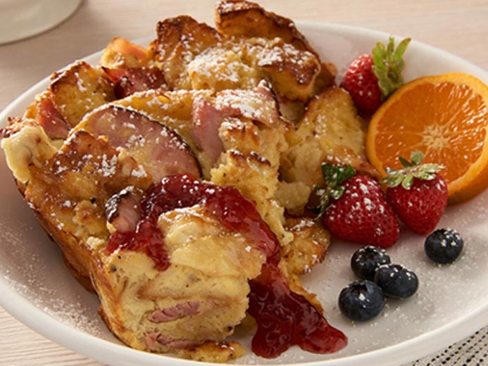 BAYS CASSEROLE WITH HAM AND EGGS ON A PLATE WITH FRUIT