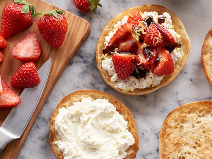 BAYS FACE UP ON A WHITE GRANITE COUNTERTOP COVERED IN WHITE CHEESE FRUIT AND A DRIZZLE